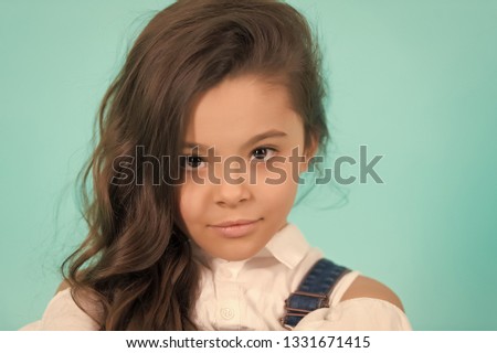 Brunette little girl pose on blue background.