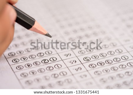 Test exam concept, pencil writing answer on paper answer of question in examination test. It assessment intended to measure knowledge, skill, aptitude, physical fitness, or classification students