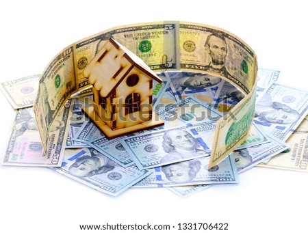 wooden house stands on a pile of paper bills dollars as a symbol of mortgage