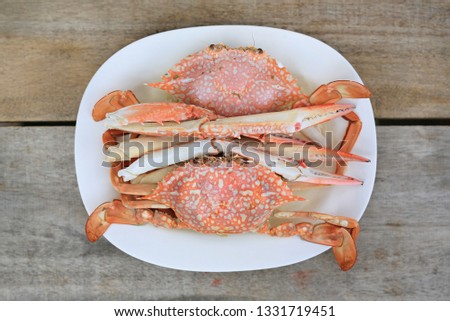 Steamed horse crab or blue crab in white plate on wood table. Seafood in Thailand. Top view.