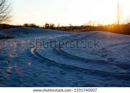 traces of a sandy road for off-road vehicles, quad bikes and motocross by the lake at sunrise with a beautiful sun 