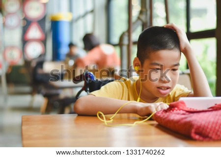 Asian special child on wheelchair is very concentrated with using a smartphone, Life in the education age of disabled children, Happy disabled kid concept.