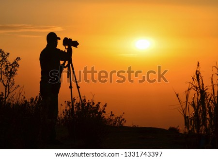 The silhouette and perspective of the tourists taking pictures are shooting the sunset at Doi Inthanon, Chiang Mai Province.