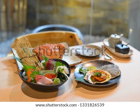 Mixed sliced fish sashimi on ice in black bowl at traditional Japanese restaurant.
