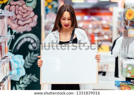 Smiling brunette woman holding white blank board
