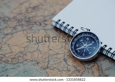 close up compass and notebook with map paper background, travel and lifestyle concept, vintage tone