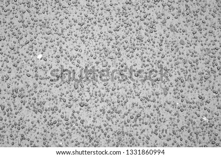 Water drops on car surface in black and white. Abstract background and texture for design.