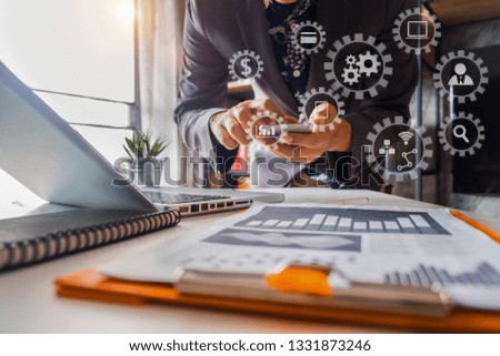 Businessman hand working digital marketing media in virtual screen with mobile phone and modern compute with VR icon diagram at office in morning light. 