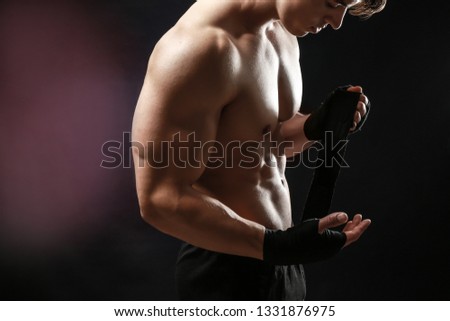 Attractive sportsman winding wrist band against dark background