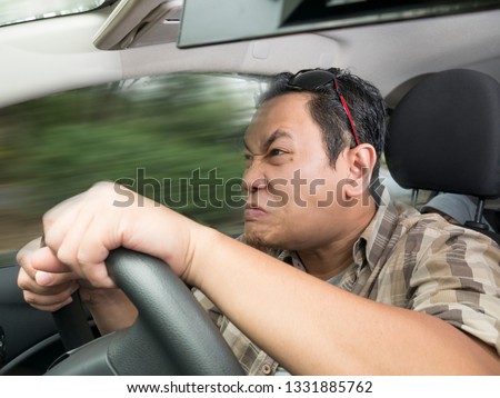 Portrait of Asian male driver mad of other car criver, speeding his car with anger dangerously,  mischievous reckless way of driving concept with motion blur Royalty-Free Stock Photo #1331885762
