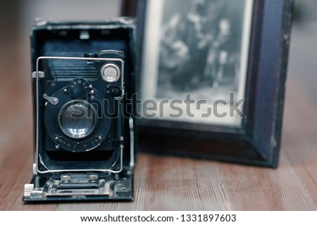 Close up image of old vintage photo camera with black and white picture on background with selective focus. Wooden table, indoors, retro effect, copy space.