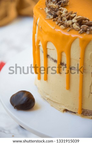 Pumpkin layer cake with chopped pecans and bright orange icing. 