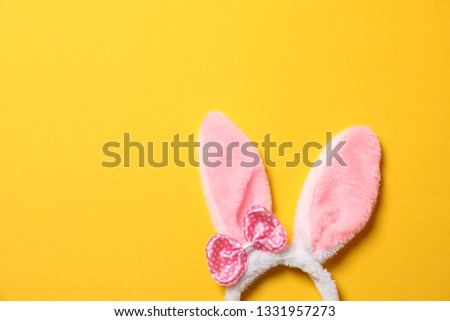 Funny headband with Easter bunny ears on color background, top view. Space for text
