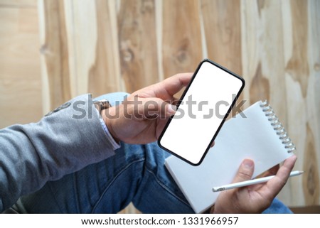 Man using mobile smartphone while writing note 