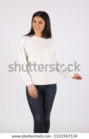 Young hipster girl girl wearing white and black cotton sweatshirt with area for your logo, mock-up of white women hoodie, white wall in the background with copy space for your design or content