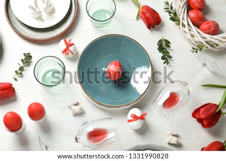 Festive Easter table setting with painted eggs on wooden background, flat lay