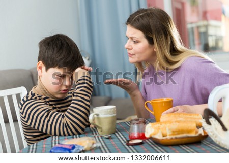 Upset mother and  unhappy son arguing during breakfast in domestic interior  Royalty-Free Stock Photo #1332006611