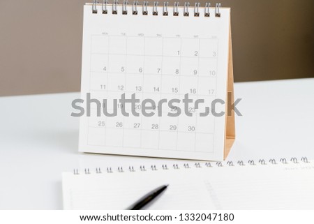 White clean desktop calendar on desk with pen and note pad using as reminder or planning.