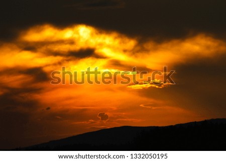 The setting sun illuminates small clouds under a thundercloud.