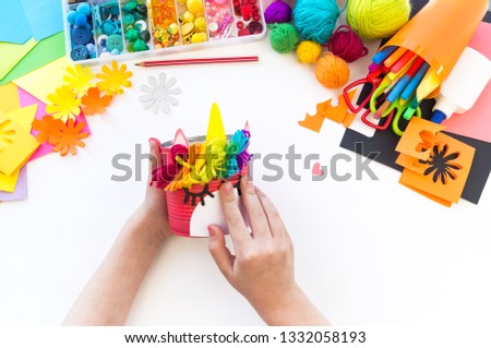 child makes a hand-made unicorn out of a tin can. Rainbow hair Favorite hobby toy. Material for creativity and tool. White background.