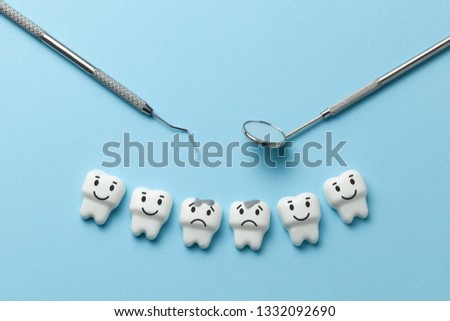 White tooth with caries on blue background  and dentist tools mirror, hook