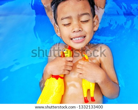 Little Asian boy having fun playing in  small kid inflatable pool