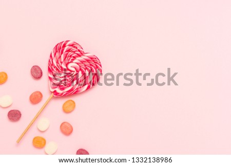 Heart Lollipop and multi coloured sweets on a gently pink background. Concept of sweets and candies. Sweet gift. Sweet love. Flat lay, top view