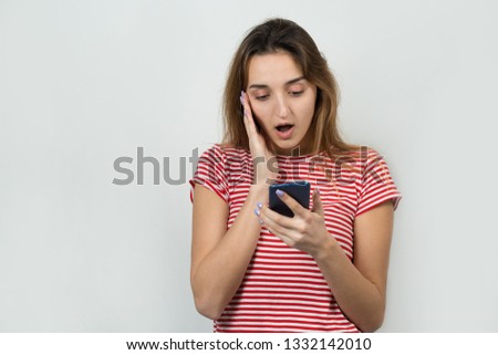 Young beautiful woman using mobile phone studio on white color background. Looking attentively at screen of cellphone, browsing web pages. 