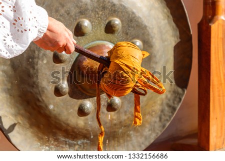 Hand hold stick and hit old brass bell in Thai Buddhism temple for respect and belief. Thai traditional, Pray by making  sound of braze circle hanging bell for religious faith.