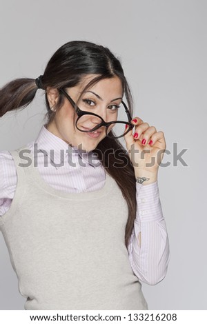 Young nerd woman playing with her glasses on white background