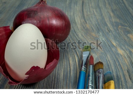 Fresh whole red onion, egg balancing in a dried onion skin. Making natural colored Easter eggs conceptual image