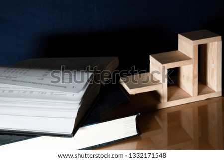 Textbook stack on wooden desk, with small wooden staircase, Education is  a step to growth with success concept.