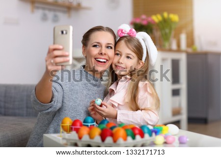 Picture of mother and daughter painting Easter eggs and taking selfie