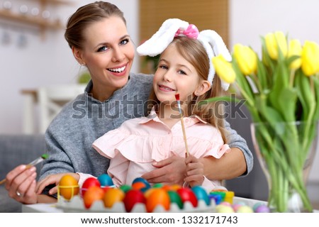 Picture of mother and daughter painting Easter eggs at home