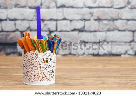 Colorful ice cream sticks in metal vase with bricks wall background. Selectively focused.