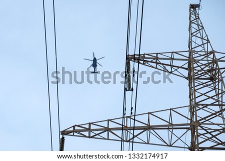 Concept helicopter flies against the blue sky and electric wires. Modern world. Iron bird and electricity. Minimalism in colors. Geometry in the image