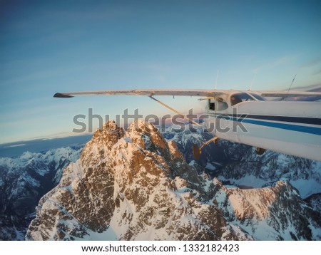 Small airplane flying near the rocky Candian Mountains during a vibrant sunset. Taken North of Vancouver, British Columbia, Canada.