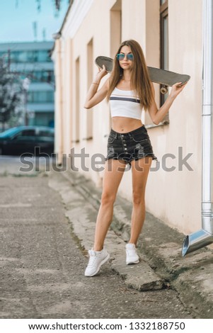 Funky girl posing with skateboard. Lifestyle outdoor portrait