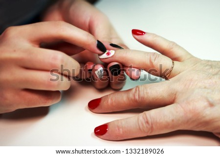 master glues a decal with a rose on the nails with a manicure with red and white lacquer. reportage shooting