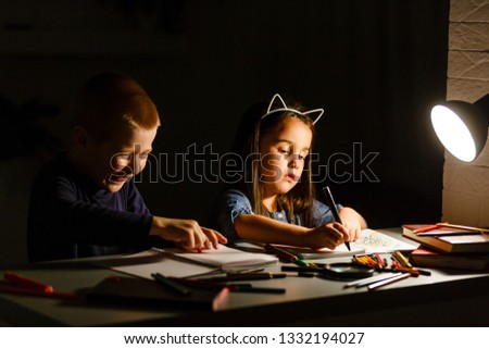 Little American girl boy doing homework in evening at home 