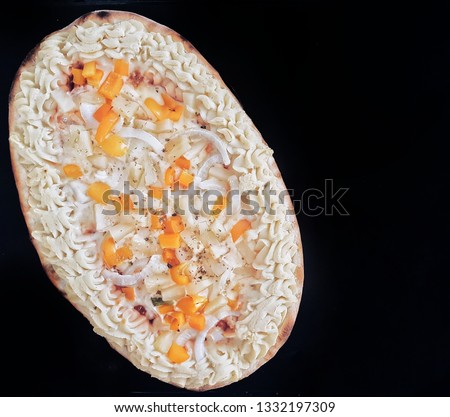 A pizza with mashed potatoe, orange bell pepper and onion isolated on black background. 