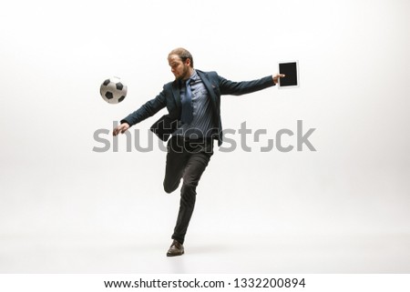 Businessman with tablet and football ball in office. Soccer freestyle. Concept of balance and agility in business. Manager perfoming tricks isolated on white studio background. Royalty-Free Stock Photo #1332200894