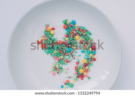 Festive abstract multicolored candy sprinkles. Yellow red green orange blue circles, doodles, flowers against white backdrop. Easter, birthday greeting card or web banner concept with copy space
