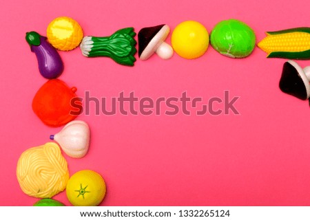 Plastic childrens toys in the form of fruit and vegetables on a pink background. Space for text. 