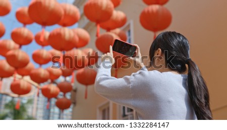 Woman take photo on cellphone with red lantern