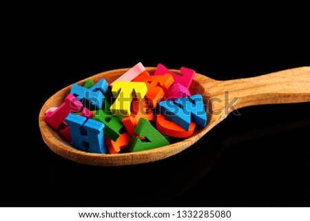 Colored letters in a spoon on a black background as a symbol of knowledge and learning