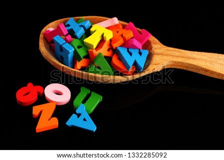 Colored letters in a spoon on a black background as a symbol of knowledge and learning