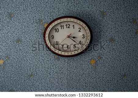 round clock with hands on the wall covered with Wallpaper