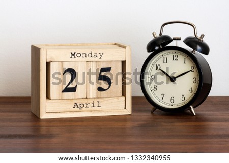 Wood calendar with date and old clock. Monday 25 April