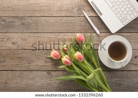 Office table with  keyboard, pen, cup of tea and flowers 